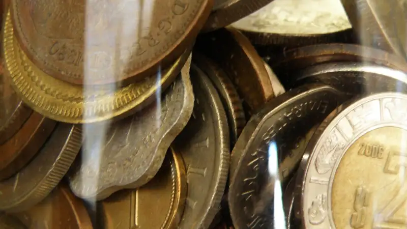 Close-up of mixed coins packed inside a clear glass jar.