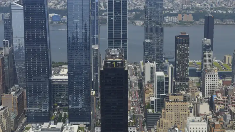 Glass office skyscrapers seen from above with a river and low-rise city beyond.