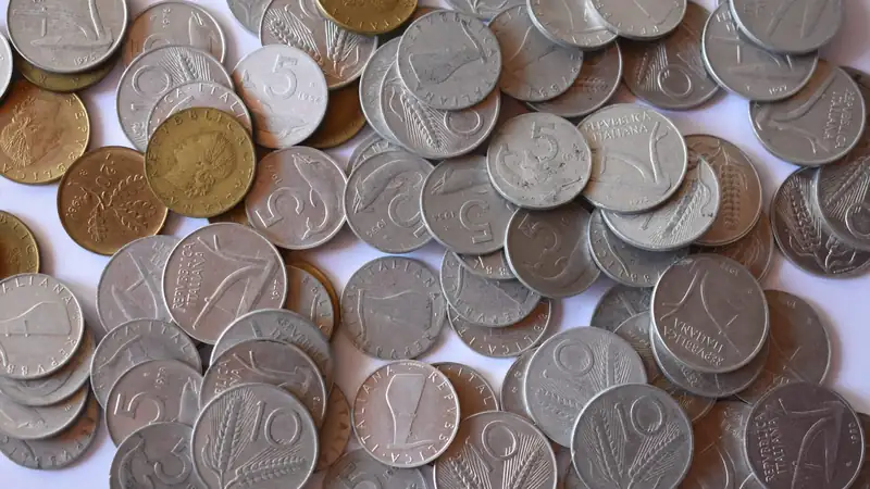 A scattered pile of old silver and bronze coins on a white surface.
